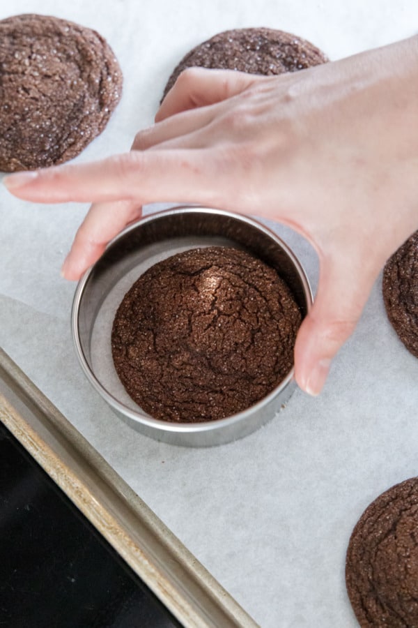 Round cookie cutter swirling around still-warm cookies to perfect the circular shapes.