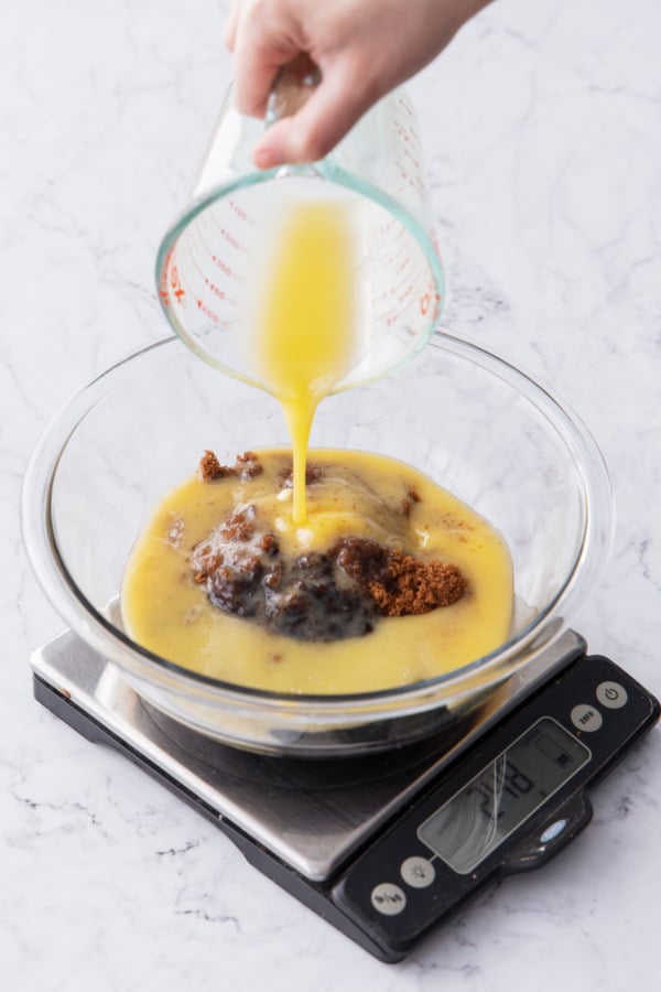 Pouring melted butter into a mixing bowl along with brown sugar and molasses.