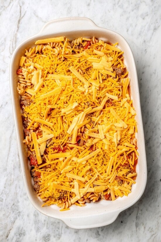 Overhead view of cheese added to cheeseburger casserole before baking