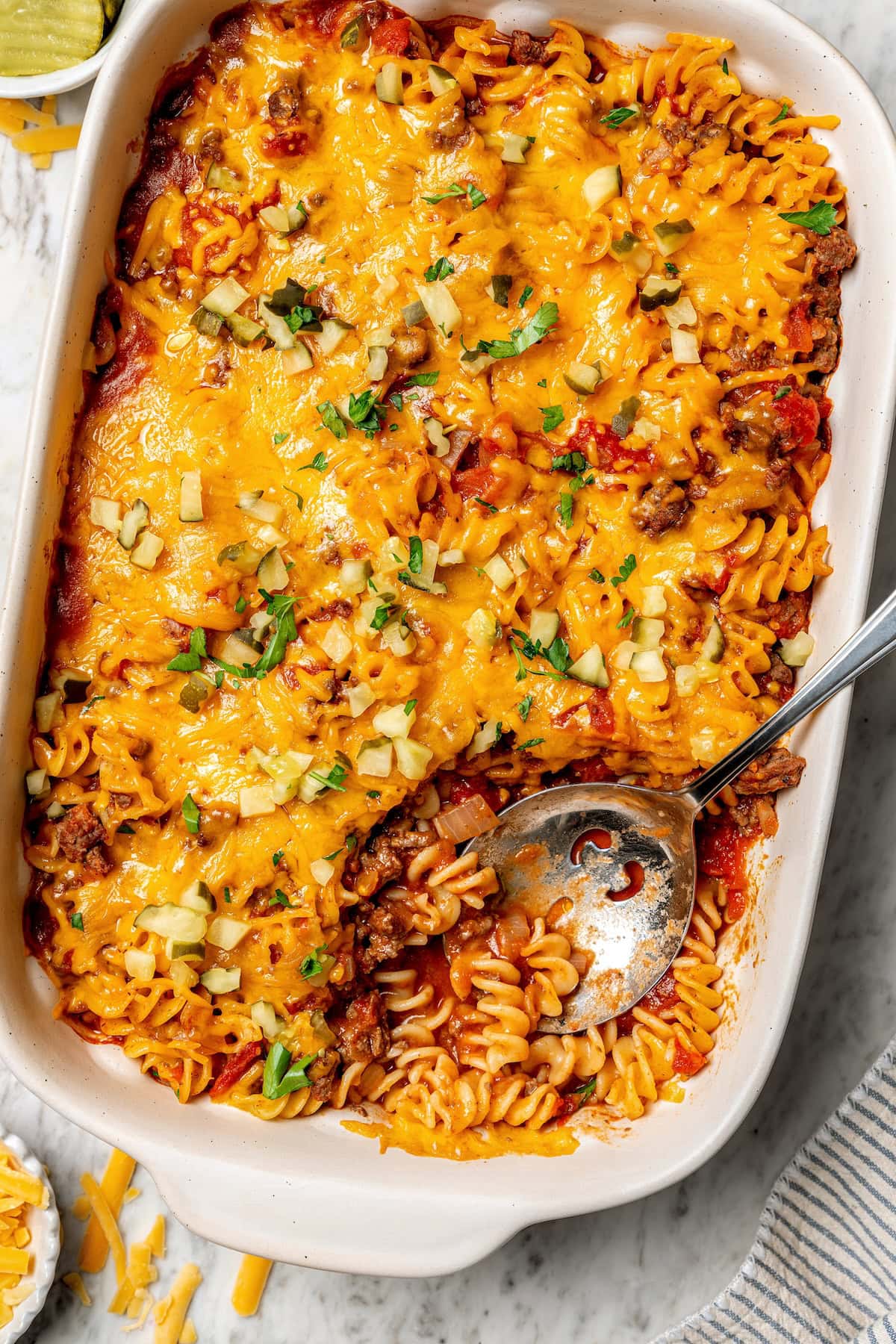 Overhead view of cheeseburger casserole in baking dish with serving spoon