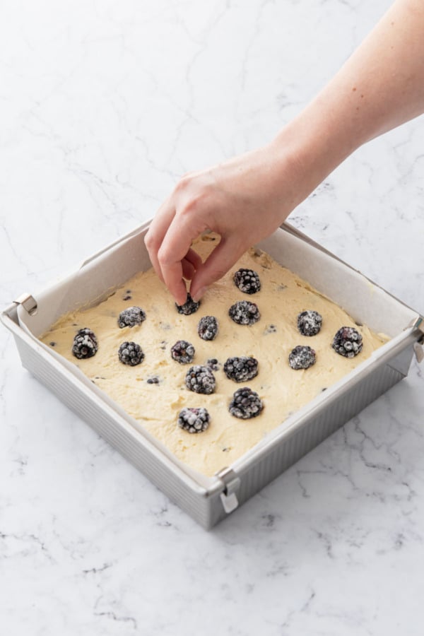 Topping final layer of cake batter with remaining fresh blackberries.