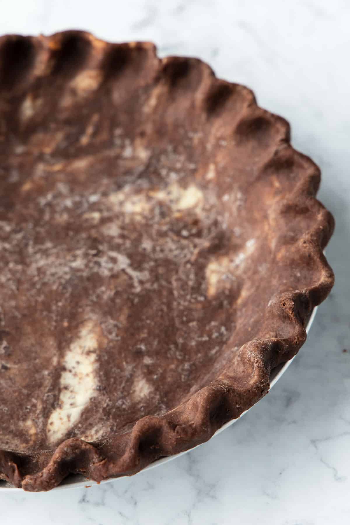 Closeup of the fluted edge of an unbaked chocolate pie crust.