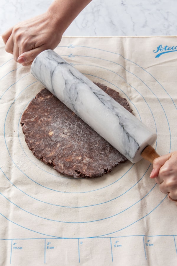 Rolling out a chocolate pie crust on a pastry cloth.