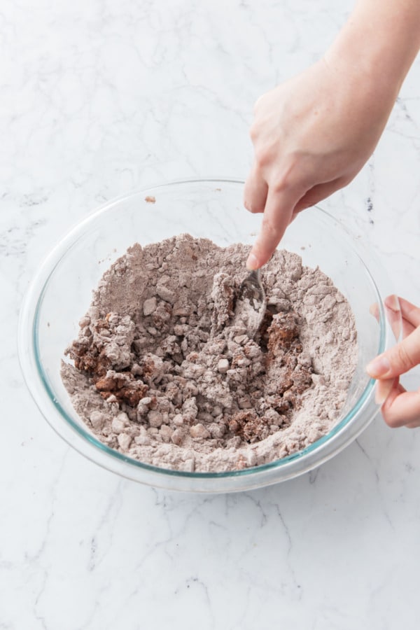 Using a fork to incorporate the water into the pie crust mixture.