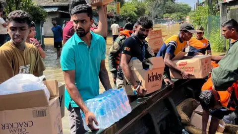 BBC Sinhala Men unloading boxes of water from a fishing boat